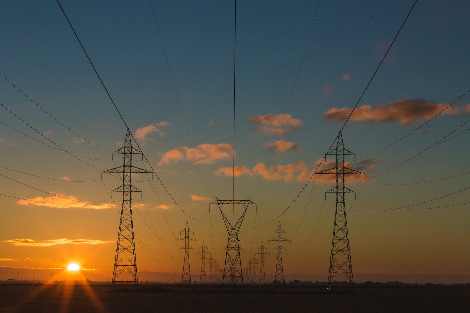 Transmission towers running toward the sunrise